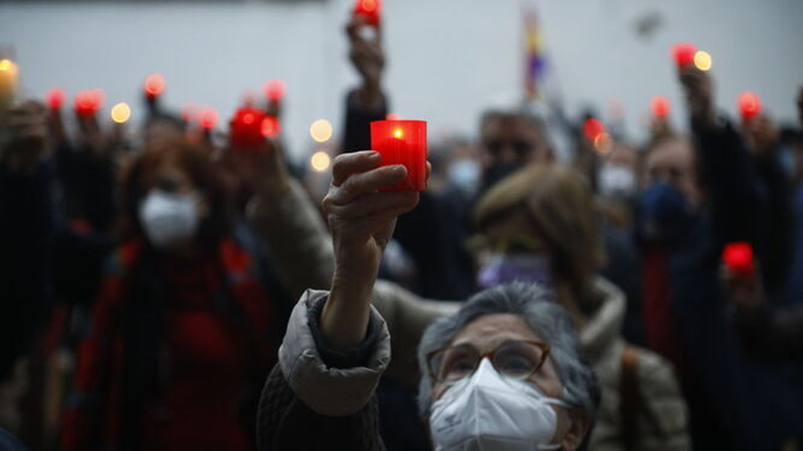 Una mujer porta una vela en un homenaje a las víctimas.