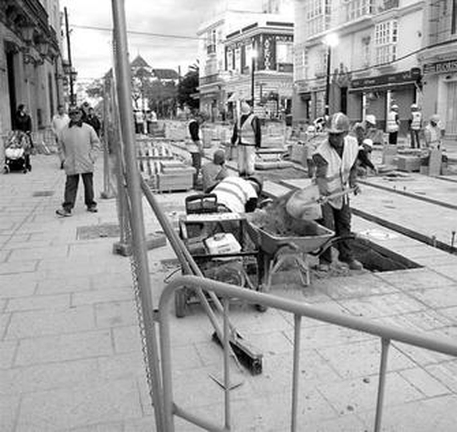 Trabajadores del tranvía, en la calle Real, se afanan cada uno en sus tareas.