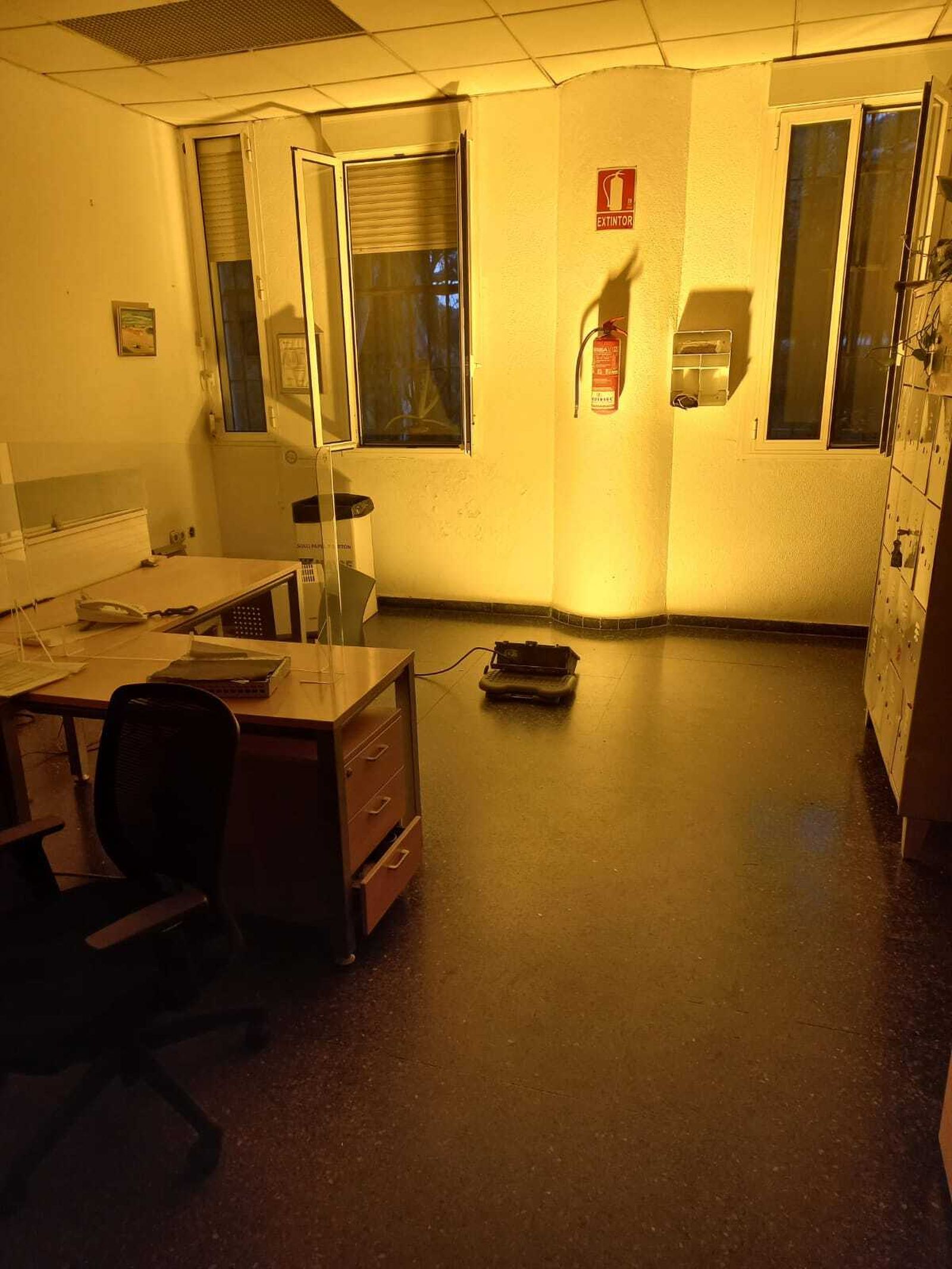 La sala de comunicaciones, iluminada parcialmente con un foco en el suelo.