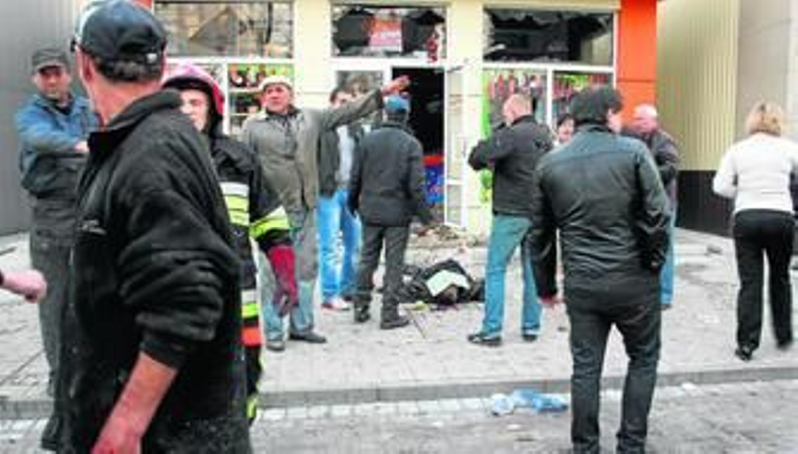 Unas personas rodean el cuerpo de fallecido por el impacto de un obús ayer en un restaurante de Donetsk.