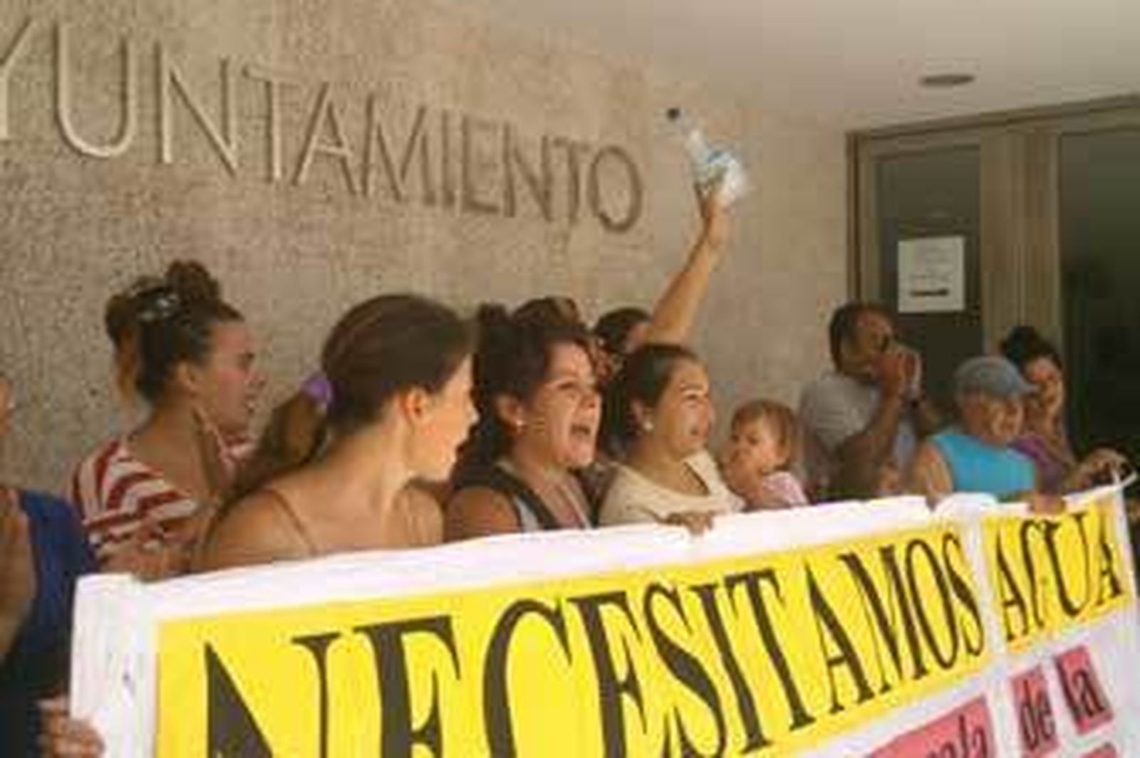 Varias mujeres que residen en la finca ocupada, ayer con una pancarta a las puertas del Ayuntamiento exigiendo suministros de luz y agua.