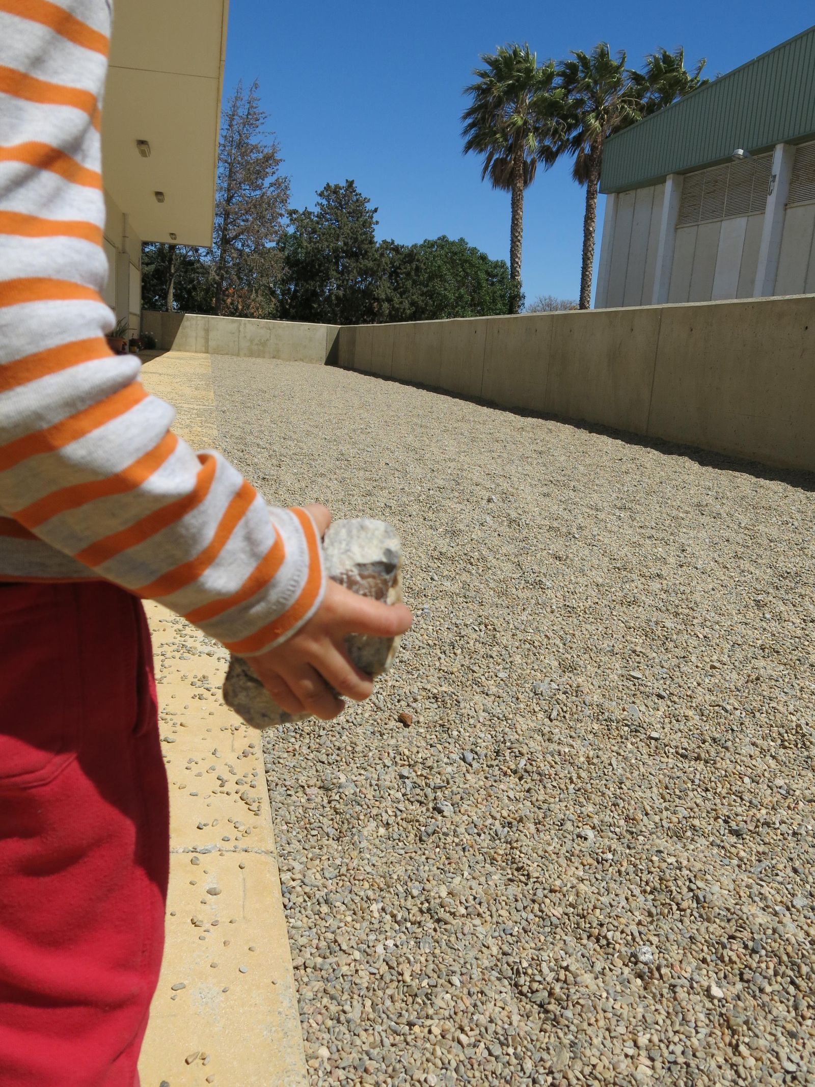 Un niño sostiene una piedra en el patio que van a techar.