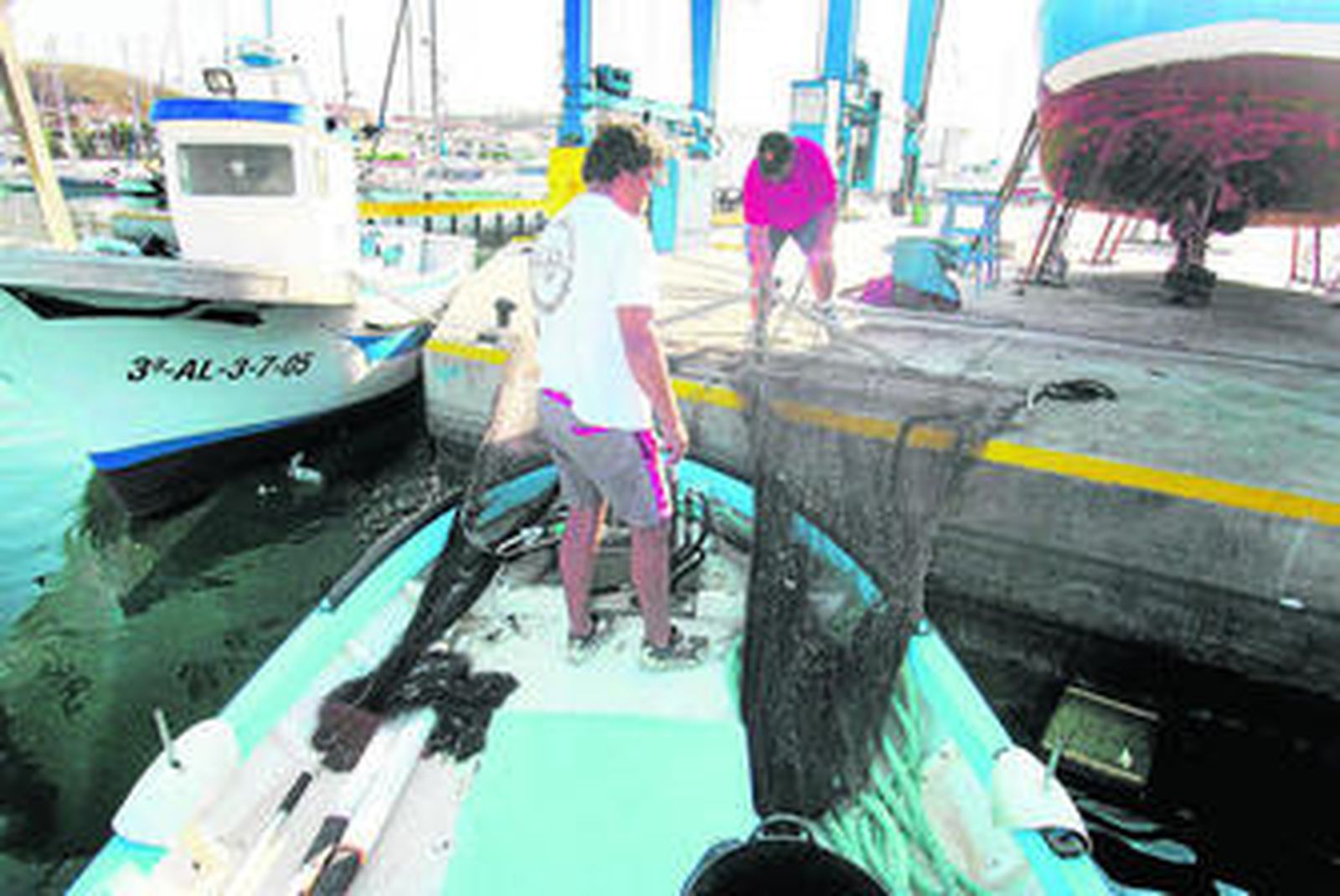 Pescadores cuidan de sus barcos en el puerto de la Caleta de Vélez.