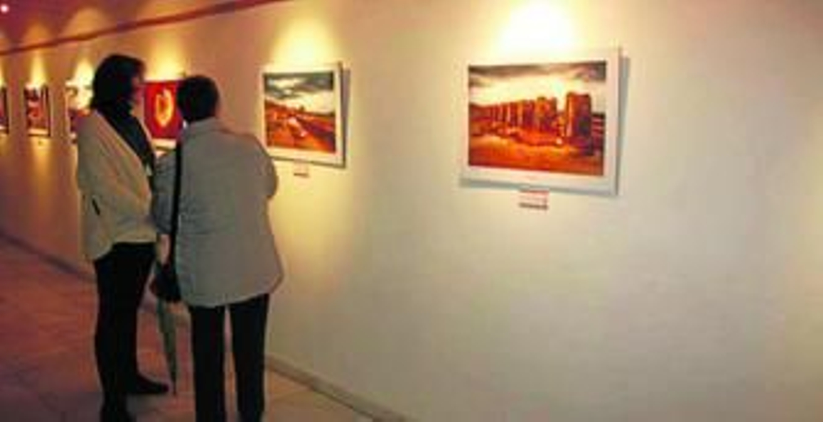 Grupos de personas viendo la exposición fotográfica y el autor posando con el cartel.