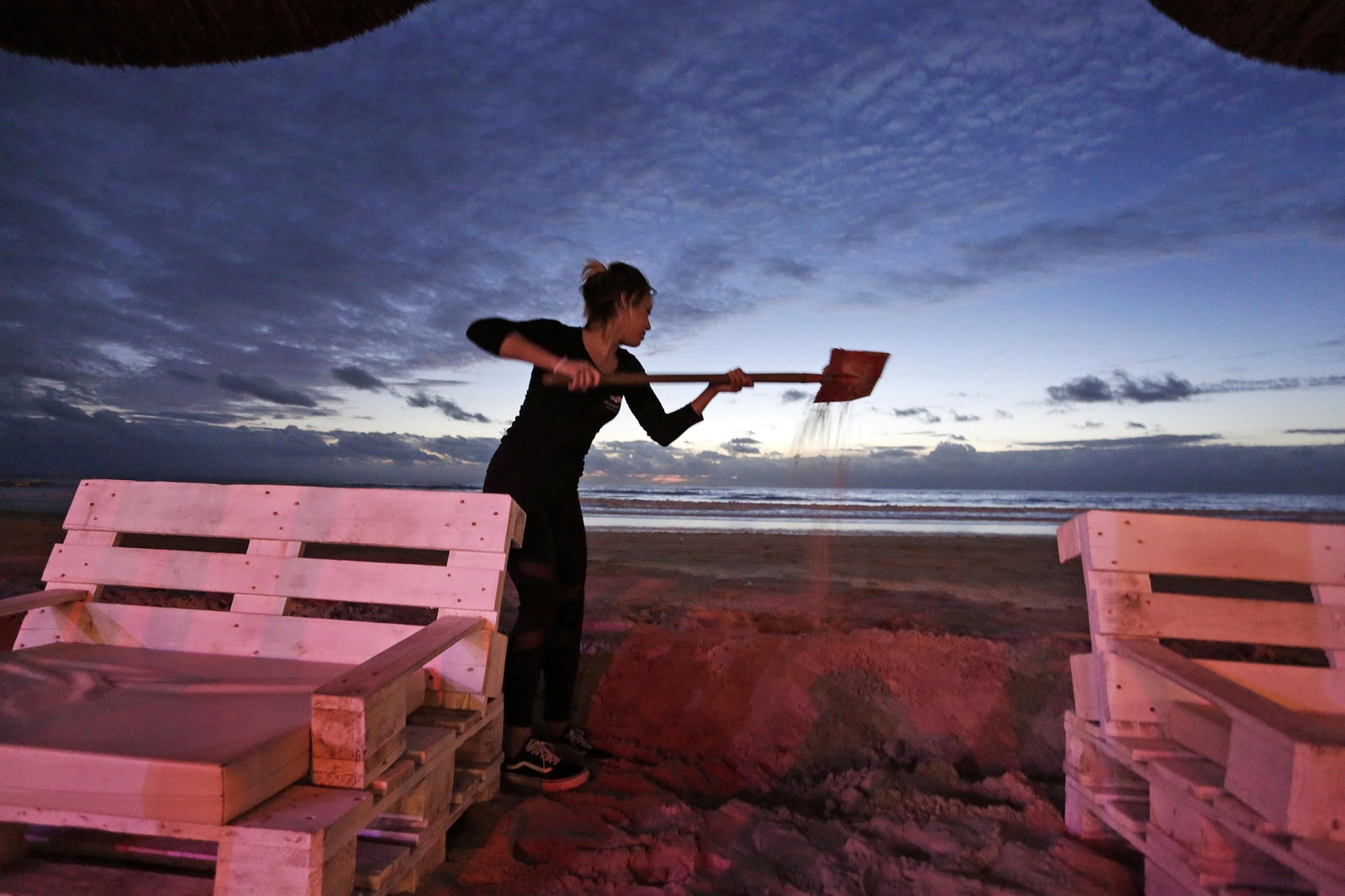 Una trabajadora despeja arena en un chiringuito de Cádiz.