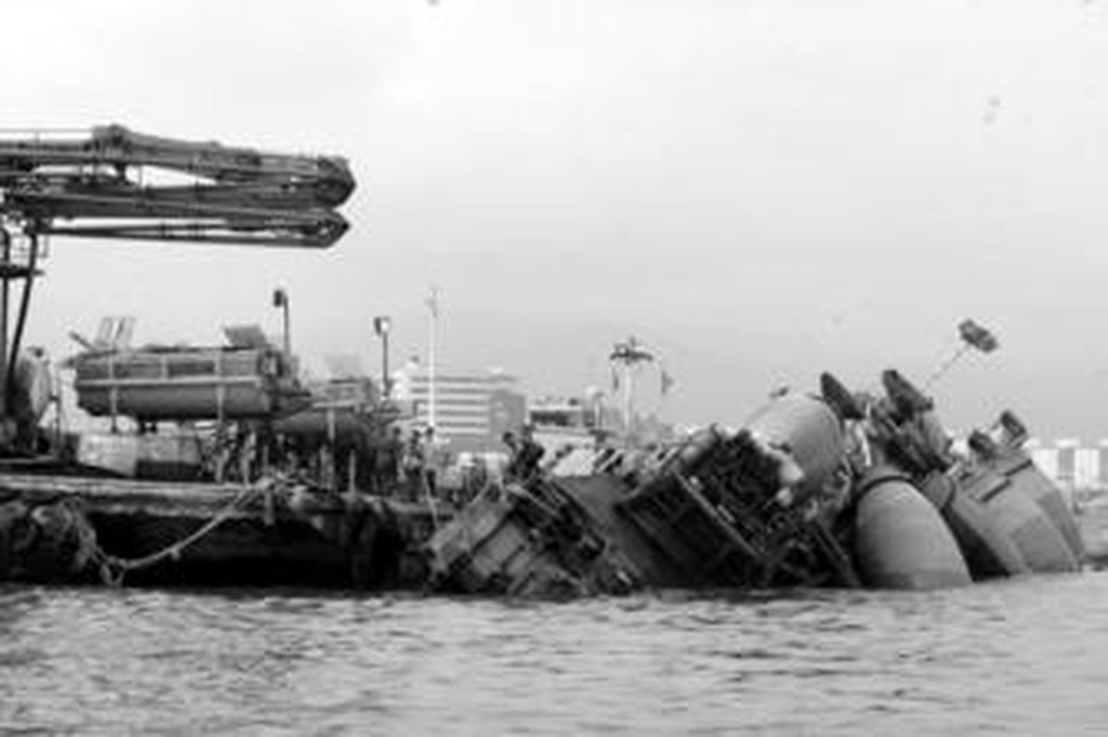 Trabajadores intentan recuperar una pontona para surtir de hormigón al dique caída tras el temporal.