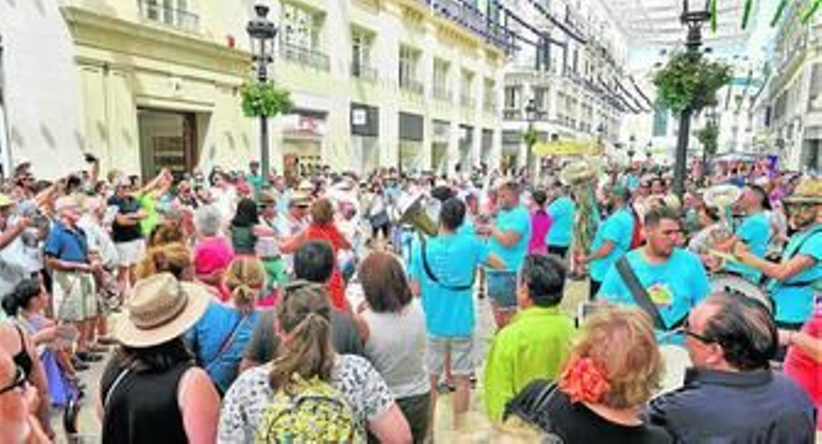 Un corro de gente rodea a una charanga en Larios.
