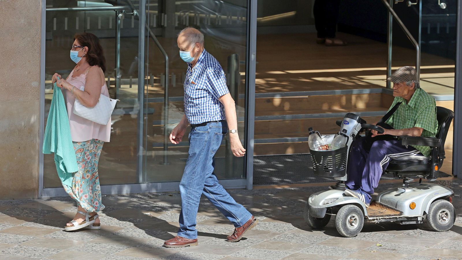 Dos personas con mascarillas en la vía pública.