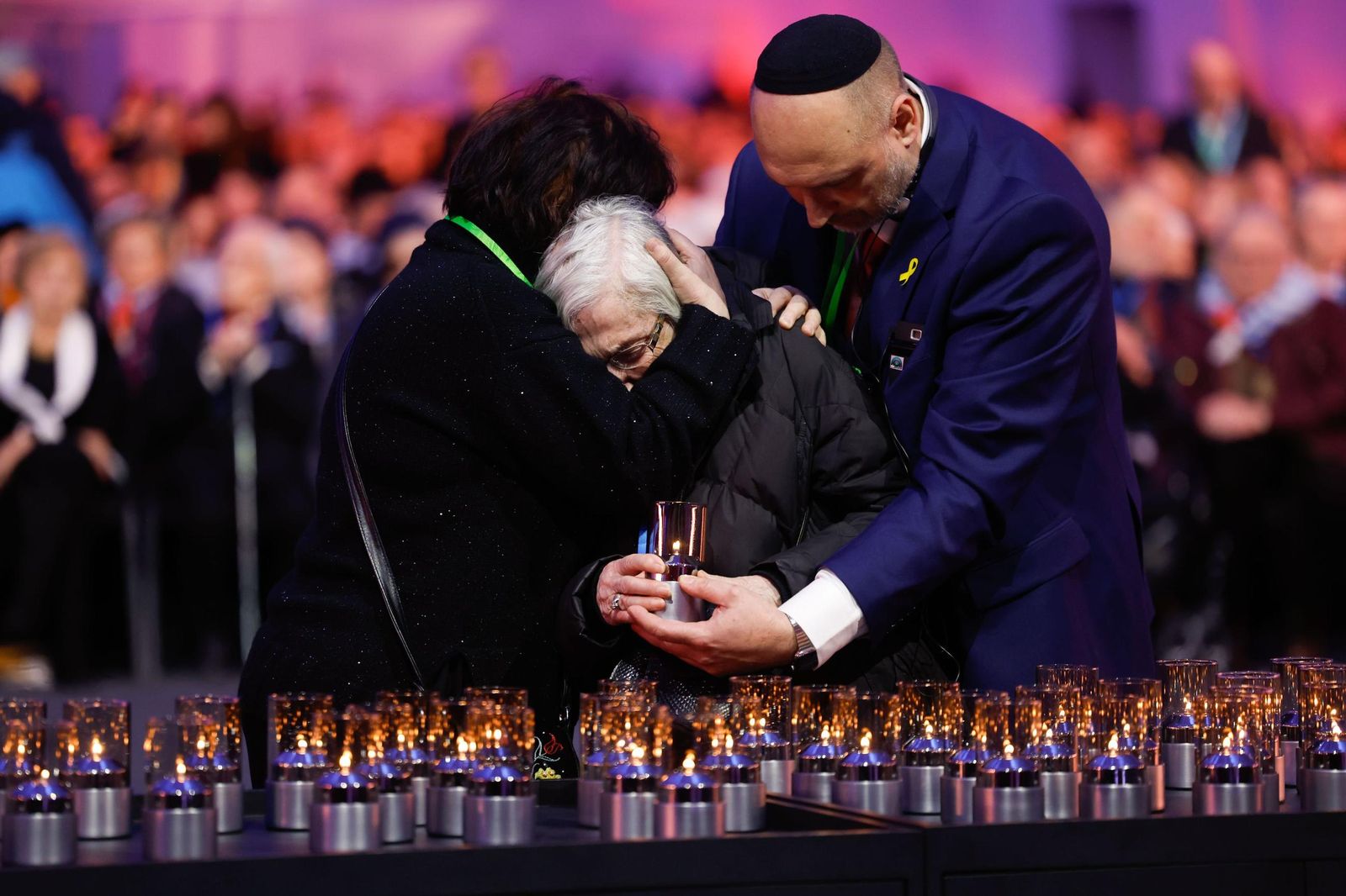 Una superviviente recibe el abrazo de sus familiares mientras enciende una vela en el acto de conmemoración del 80 aniversario de la liberación de Auschwitz.