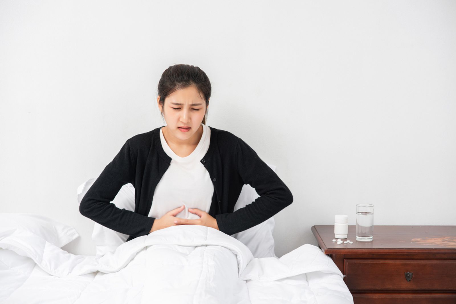 Mujer en la cama con dolor abdominal