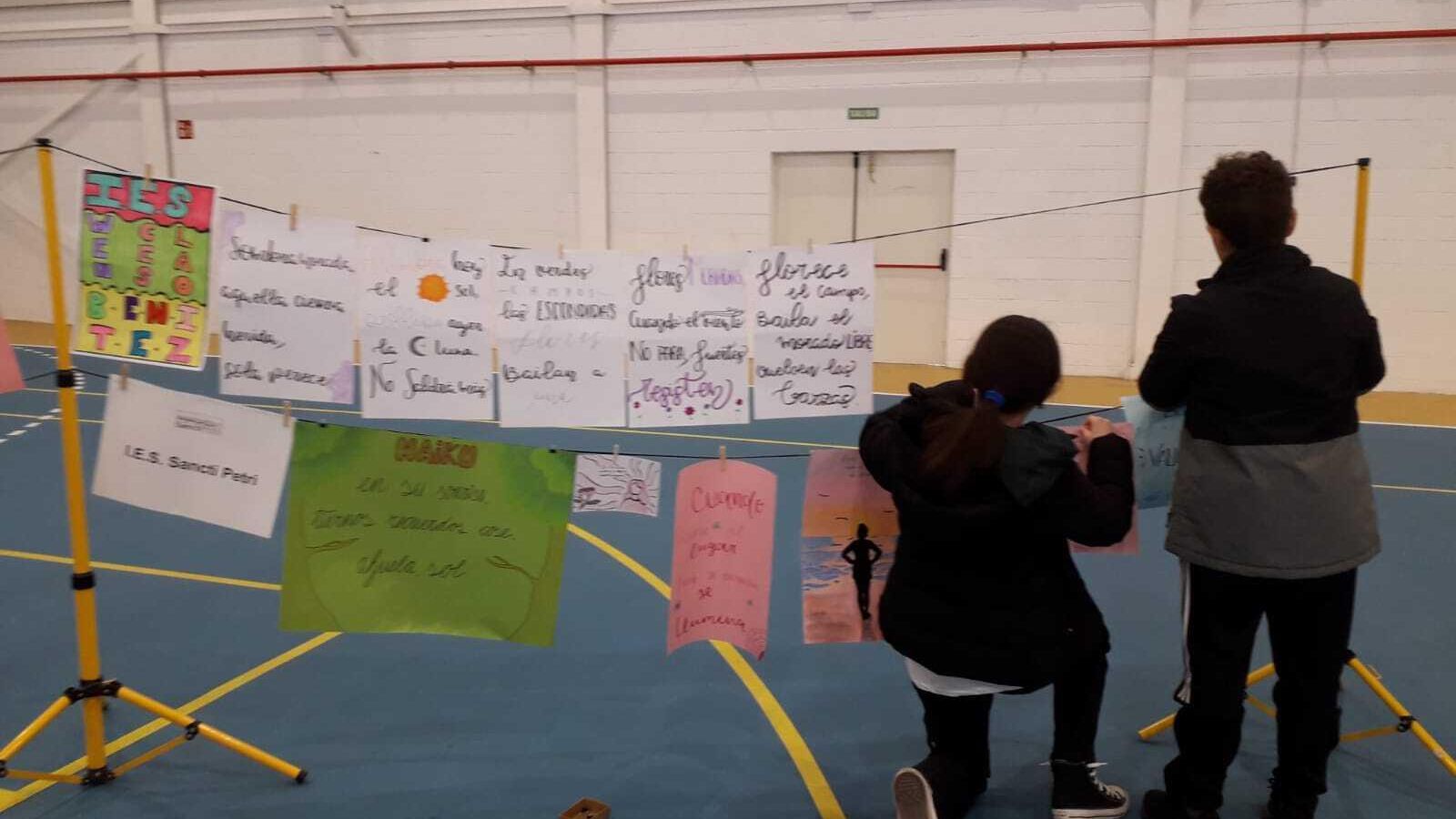 Unos alumnos colocan algunos de los haikus escritos por estudiantes para el acto del 8M.