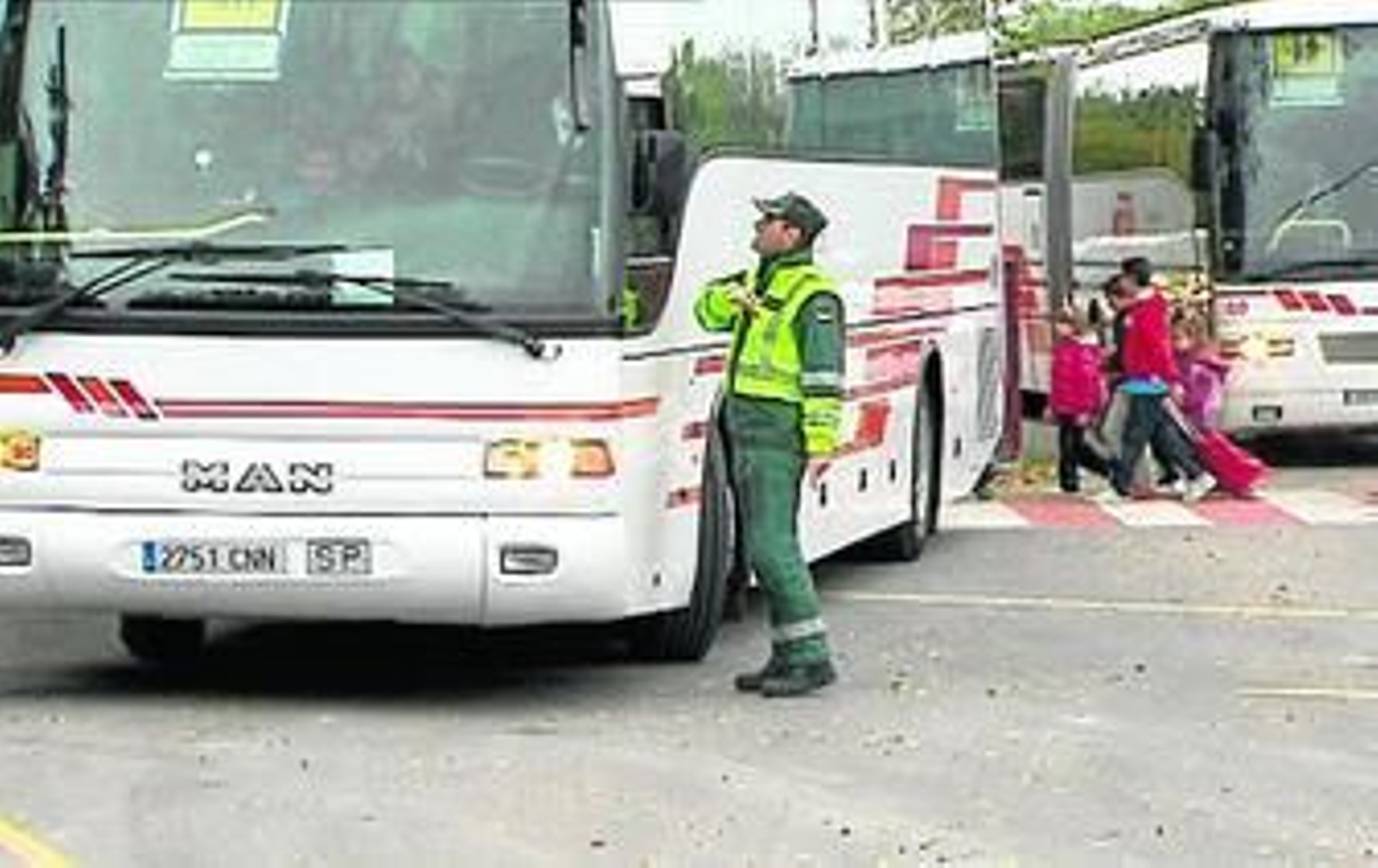 Un agente de la Guardia Civil habla con el conductor de un autobús escolar.