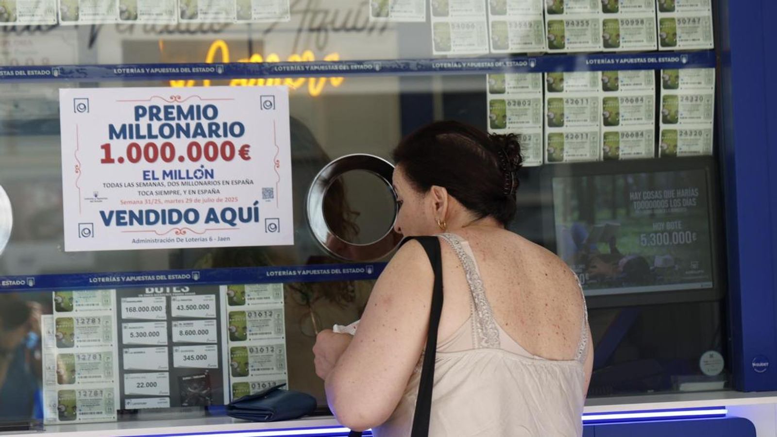Mujer compra un boleto de lotería en la administración que ha repartido el premio. Mujer compra un boleto de lotería en la administración que ha repartido el premio.