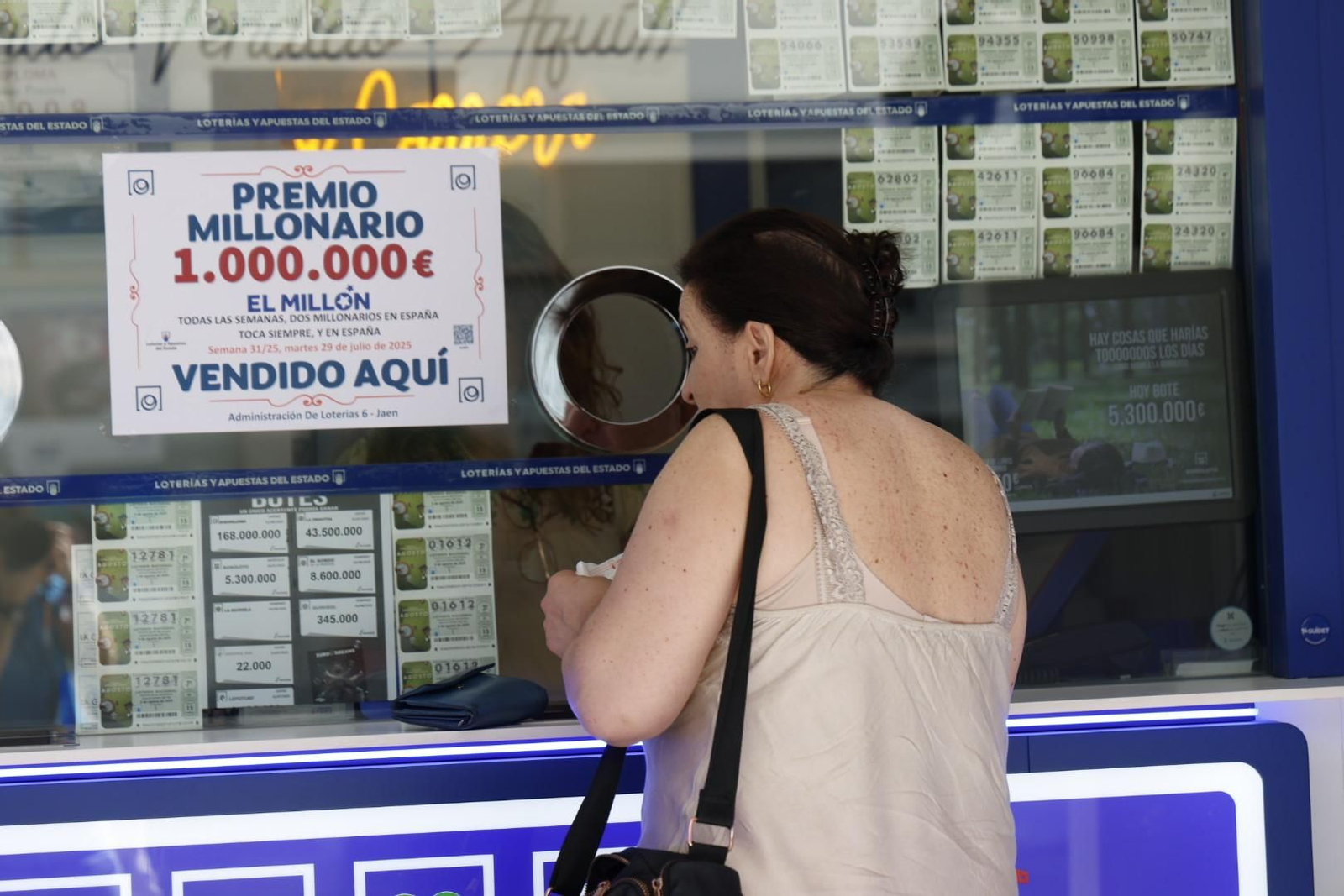 Mujer compra un boleto de lotería en la administración que ha repartido el premio.