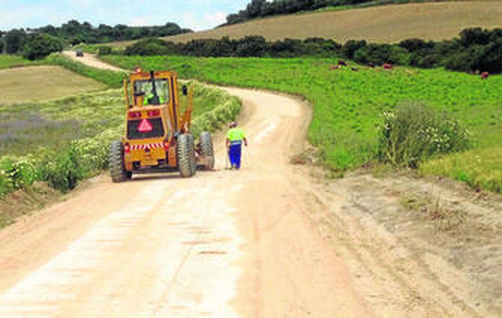 Una máquina y un operario preparando el terreno para su asfaltado.