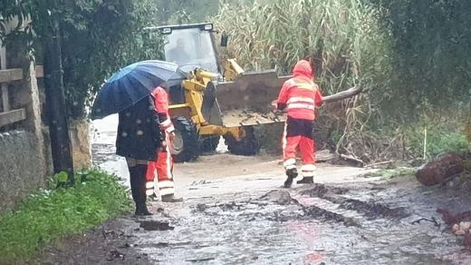 Los trabajadores municipales  quitan barro durante las lluvias.