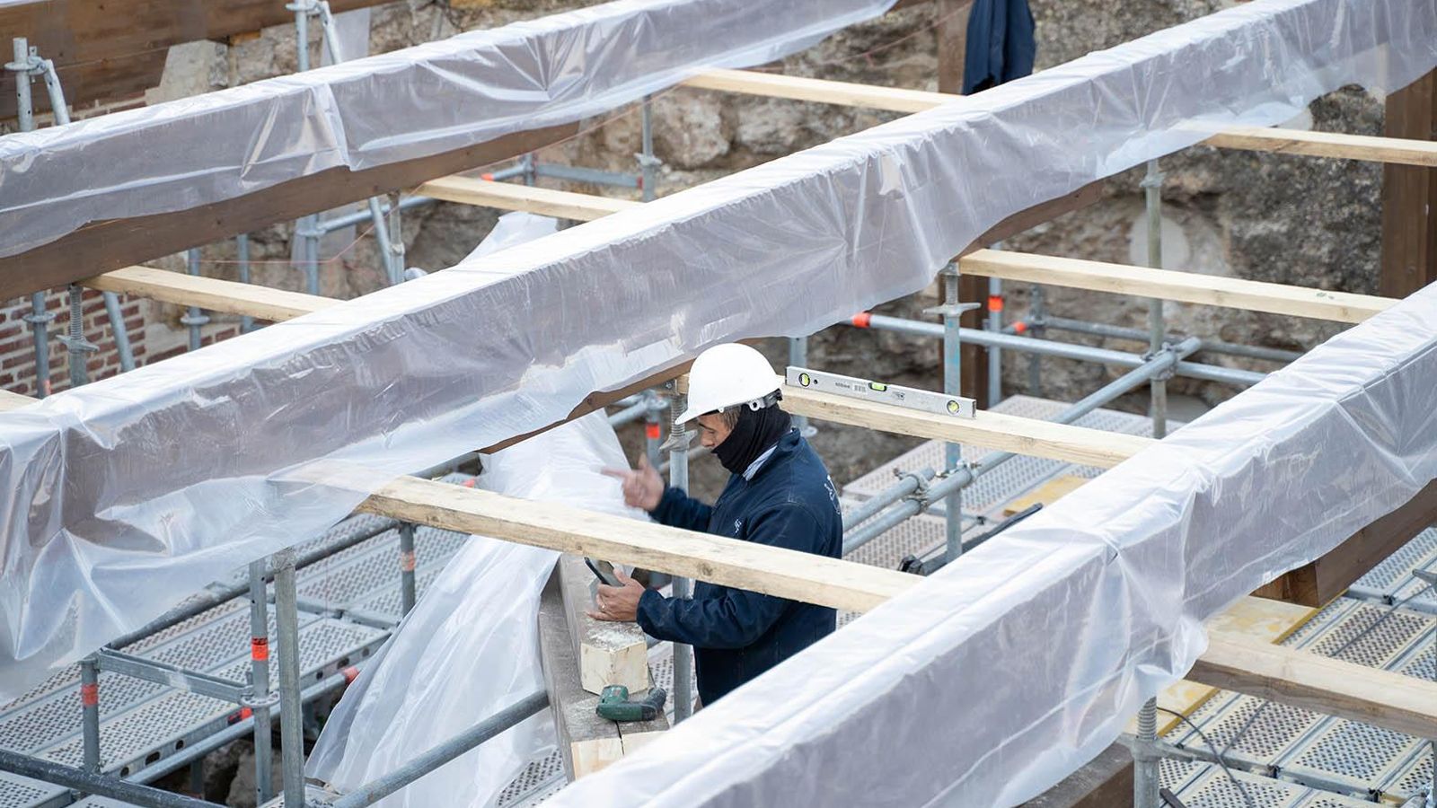Un trabajador corta madera bajo la estructura