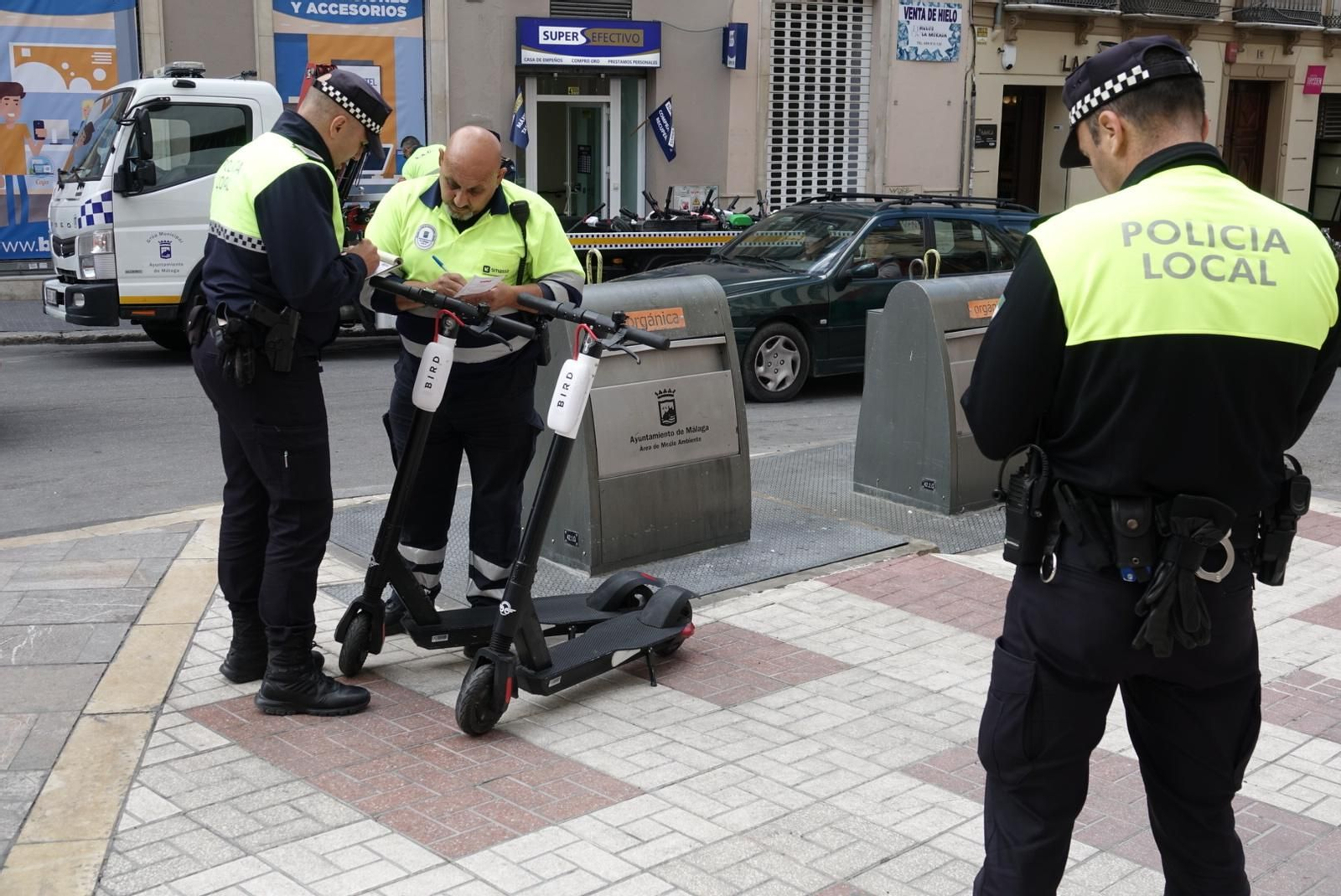 Dos policías locales observan unos patinetes en la calle