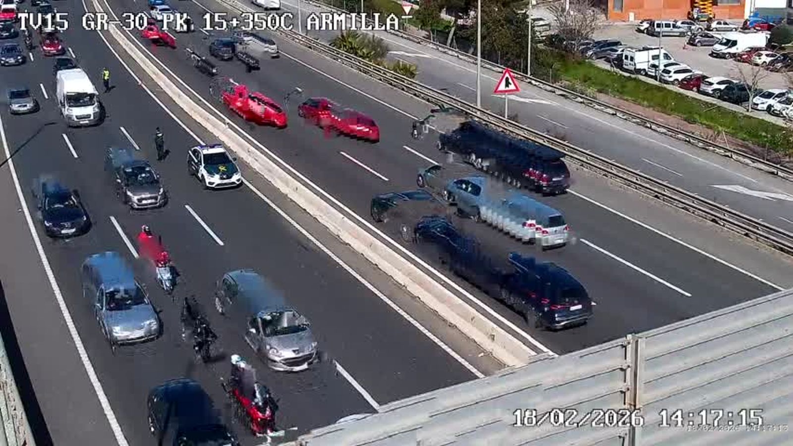 Un vehículo de la Guardia Civil de Tráfico y dos agentes desvían el tráfico del carril izquierdo de la GR-30 en el lugar del accidente