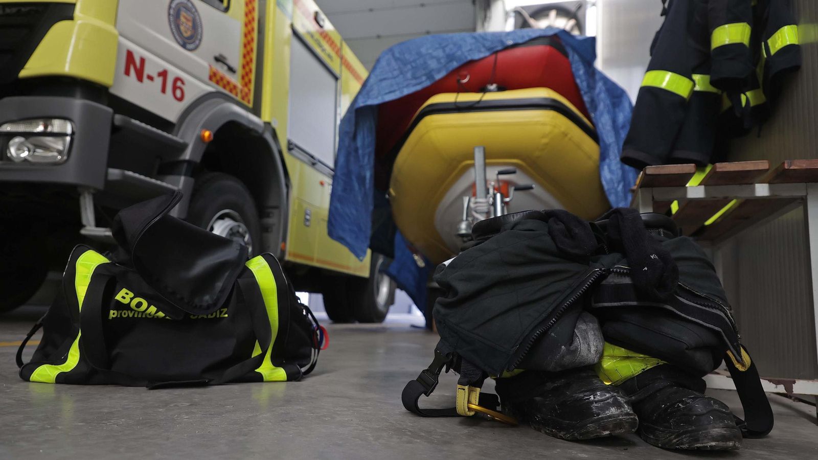 En primer plano, botas y ropa de un bombero preparadas para una salida.