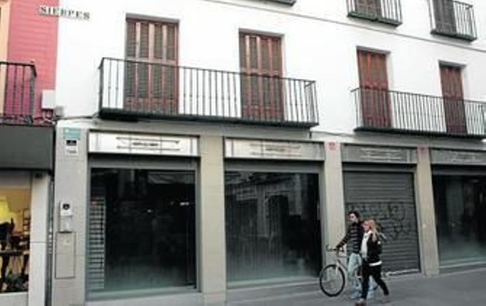 Un ciclista pasea a pie con una acompañante en la mañana de ayer por una calle peatonal del centro.