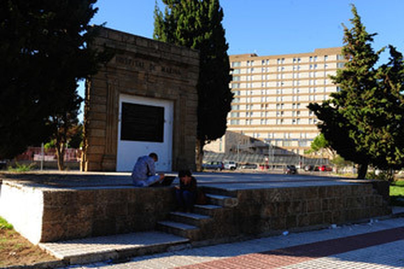 Puerta del antiguo hospital de San Carlos y, al fondo, las instalaciones actuales.