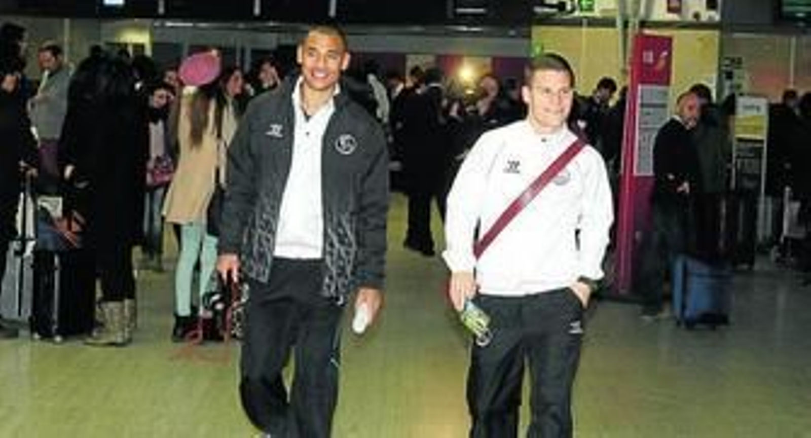 Kolodziejczak y Gameiro, sonrientes, caminan por el aeropuerto de San Pablo con la tarjeta de embarque en la mano.