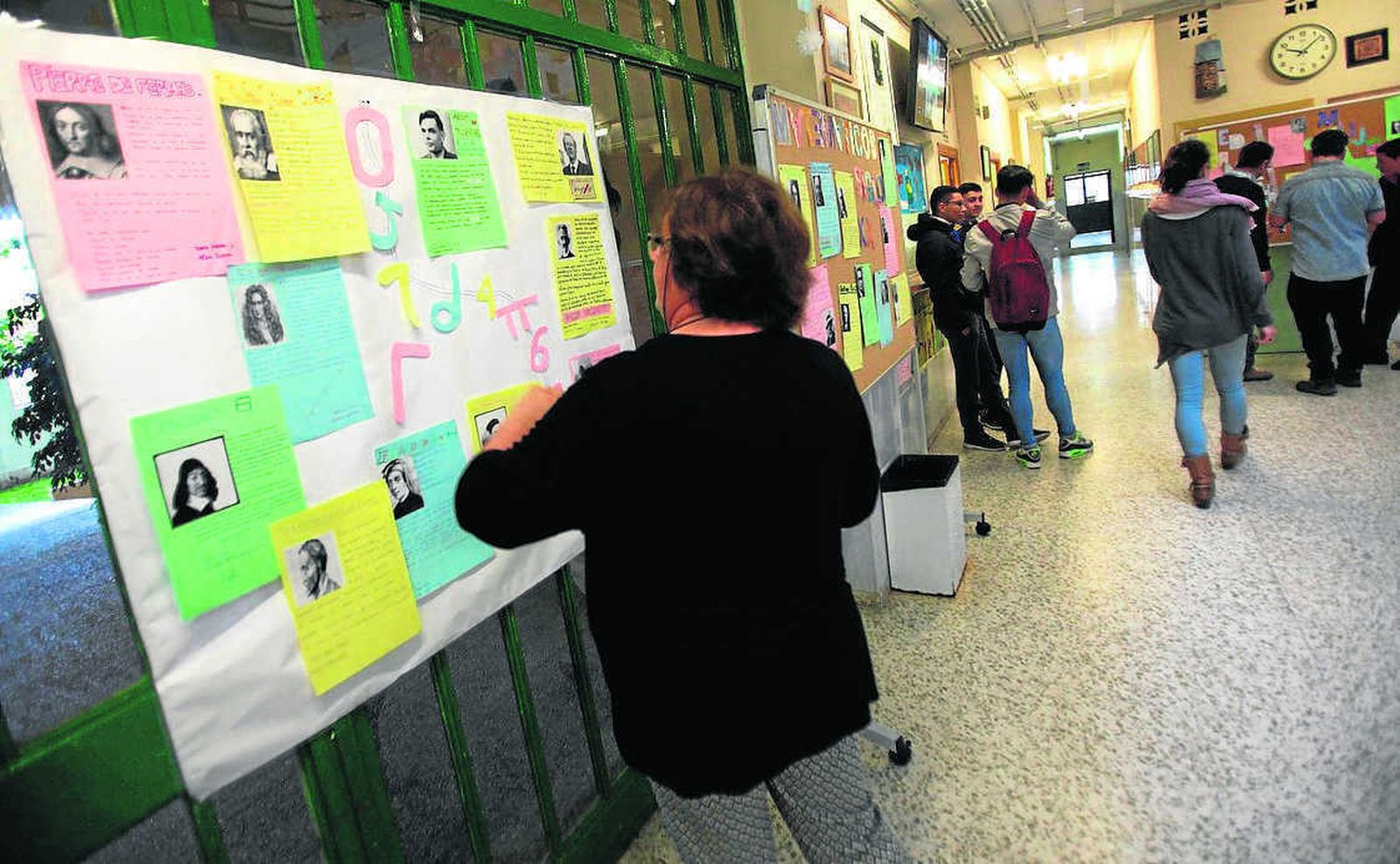 Una profesora instala un panel en la entrada del centro.