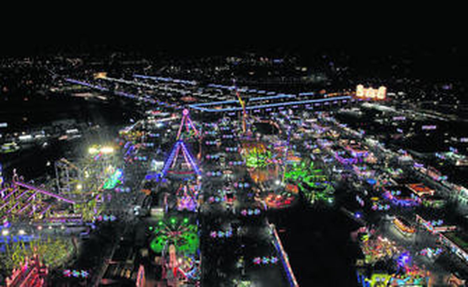Panorámica del recinto ferial de Cortijo de Torres desde la gran noria, con la portada principal del Hotel Miramar iluminada al fondo.