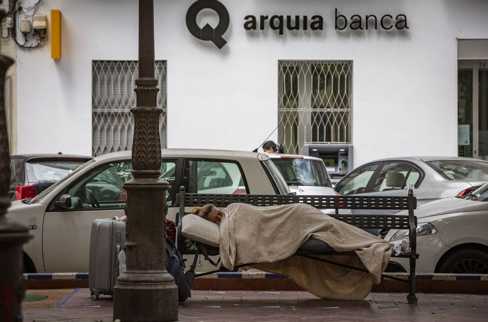 Un indigente instalado en unos de los bancos de la zona central de la plaza