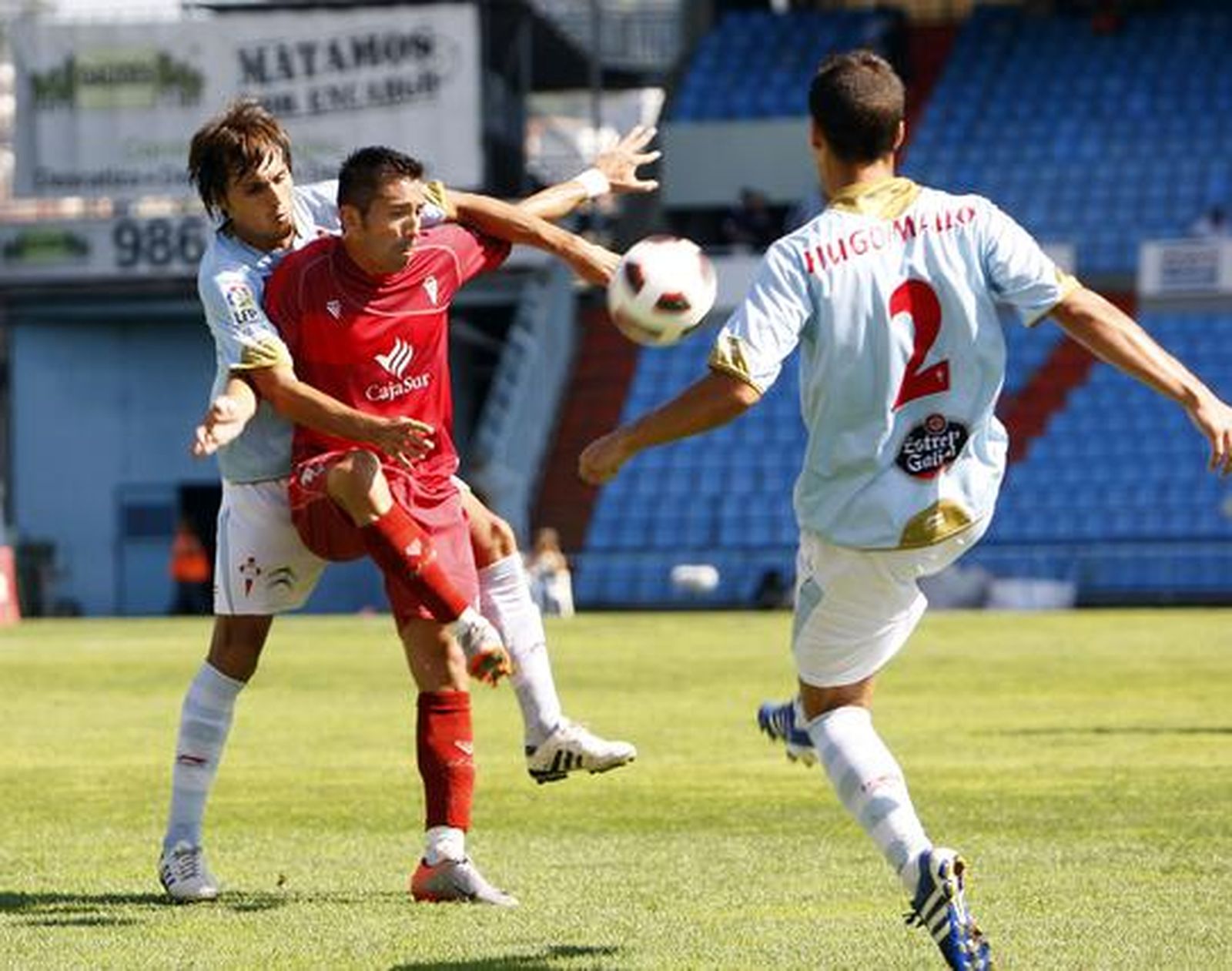 Un jugador del Córdoba trata de controlar entre dos rivales. / Marta G. Brea
