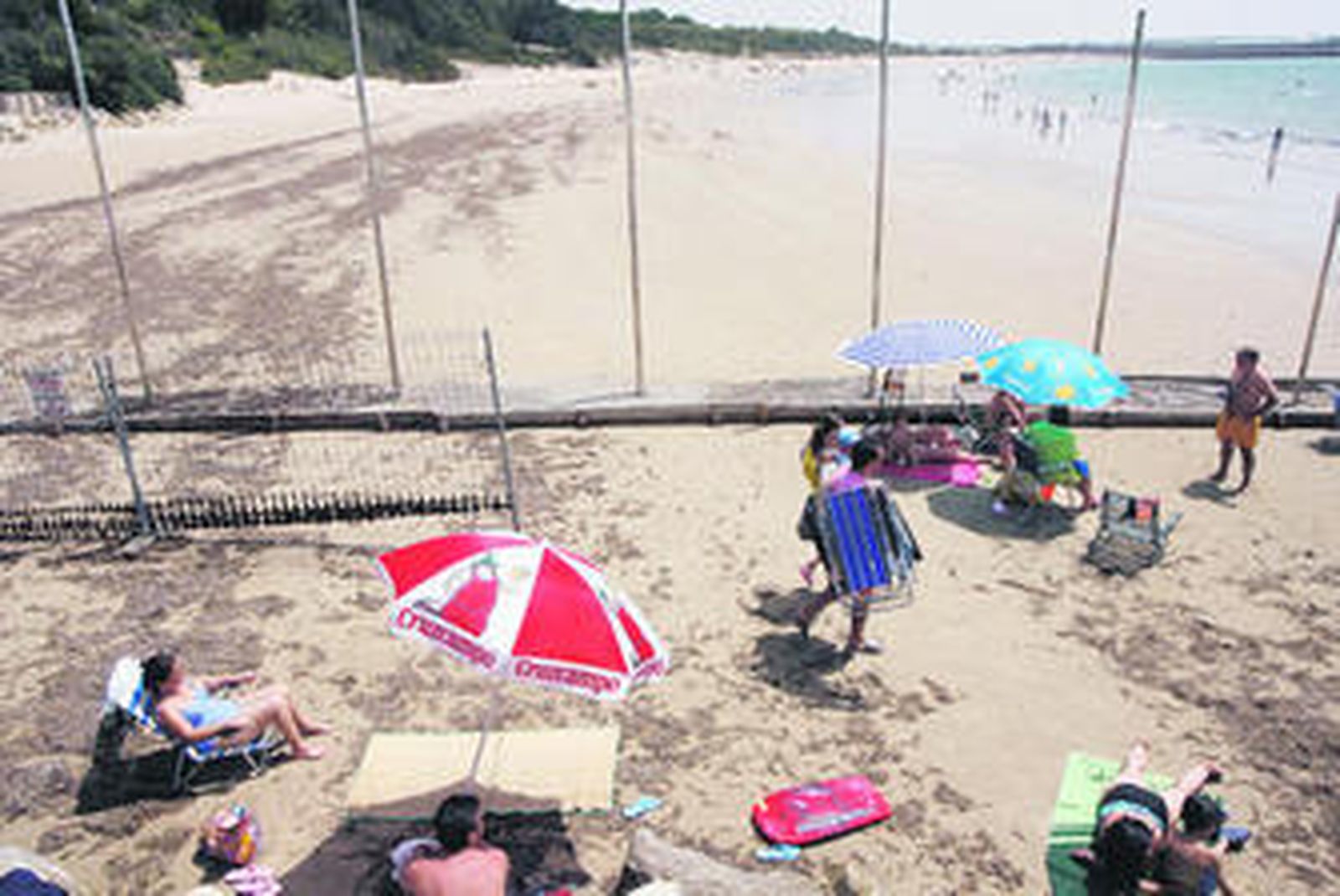 Usuarios del Chorrillo junto a la nueva valla que se proyecta sobre la playa del Almirante, enla Base de Rota.
