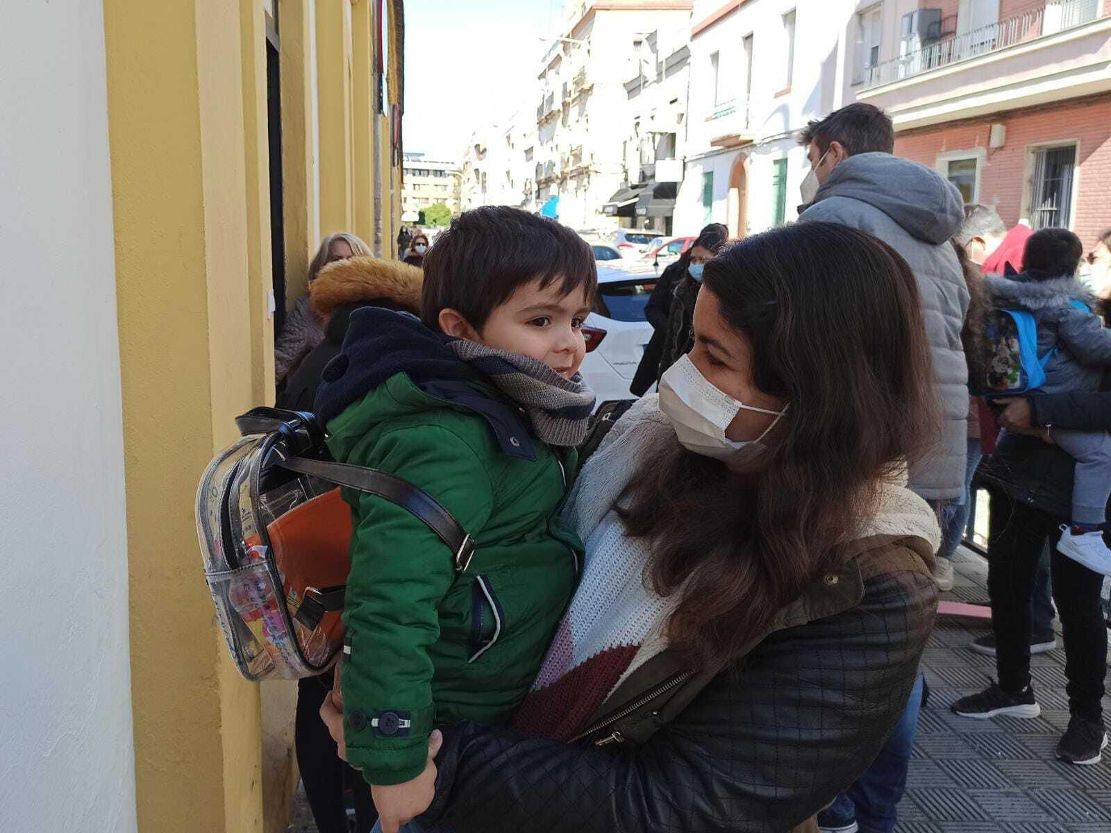 Una madre lleva a su hijo, con abrigo y bufanda, al CEIP Borbolla tras aconsejarlo el equipo directivo.
