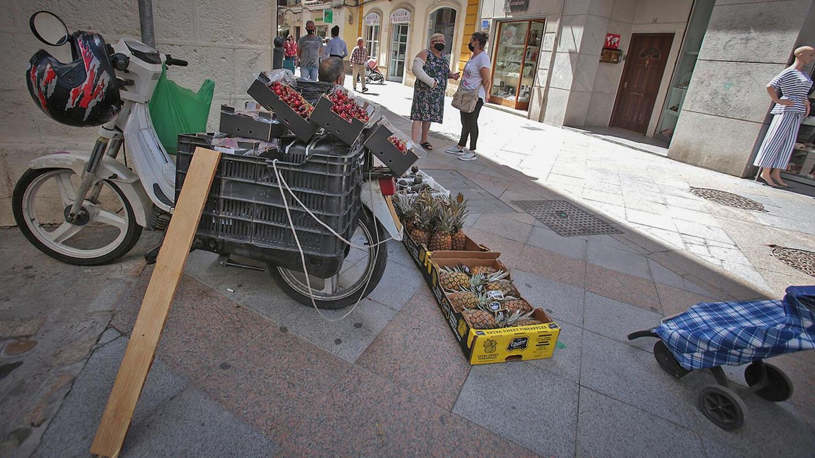 Cajas de frutas en el suelo y sobre una moto para su venta ambulante en Doña Blanca.