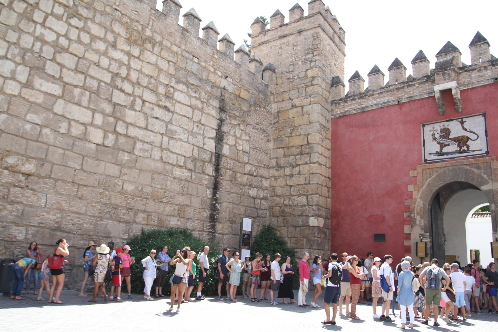 Un grupo de turistas haciendo cola junto a las murallas para acceder al Real Alcázar.