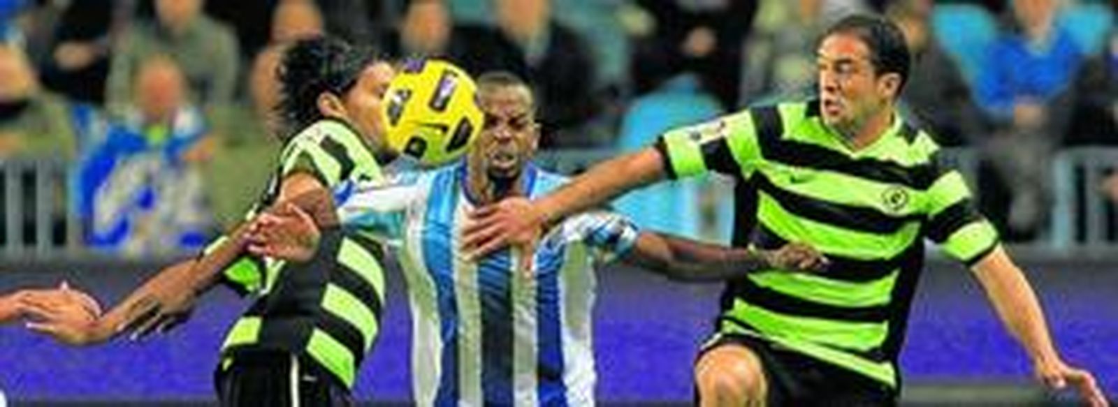 Sandro Silva trata de zafarse de la vigilancia de dos jugadores del Hércules durante un partido de la pasada Copa del Rey con el Málaga.