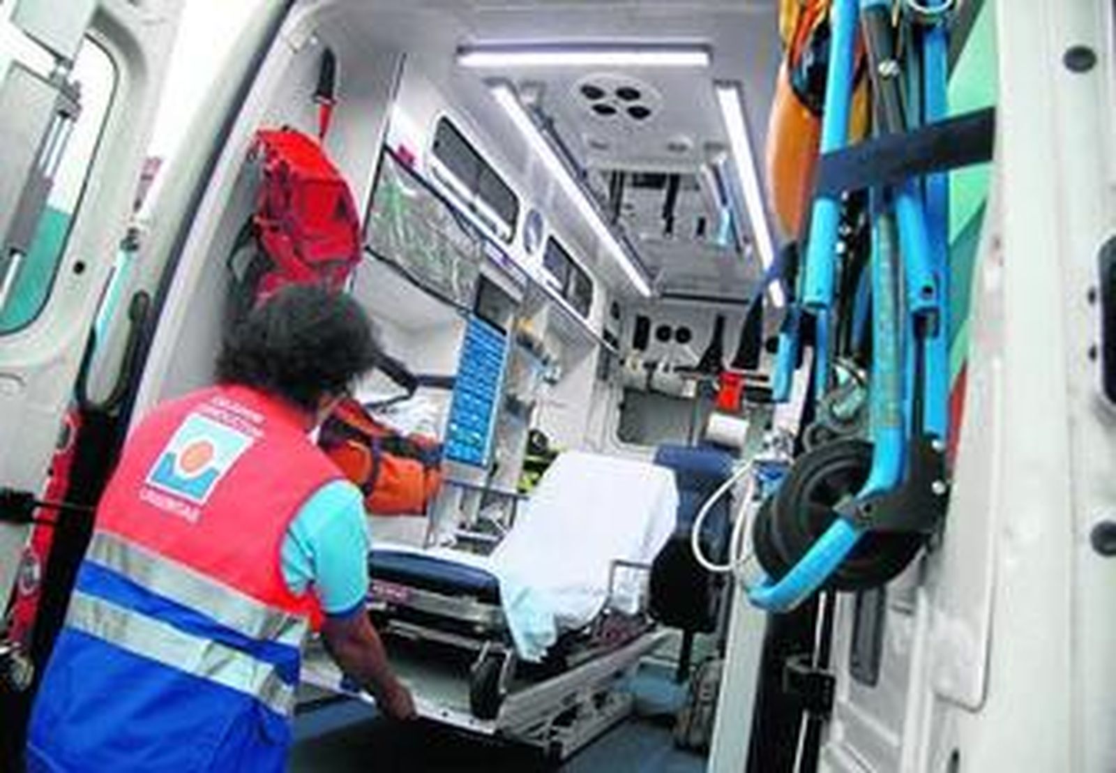 Un conductor de urgencias coloca la camilla en la ambulancia.