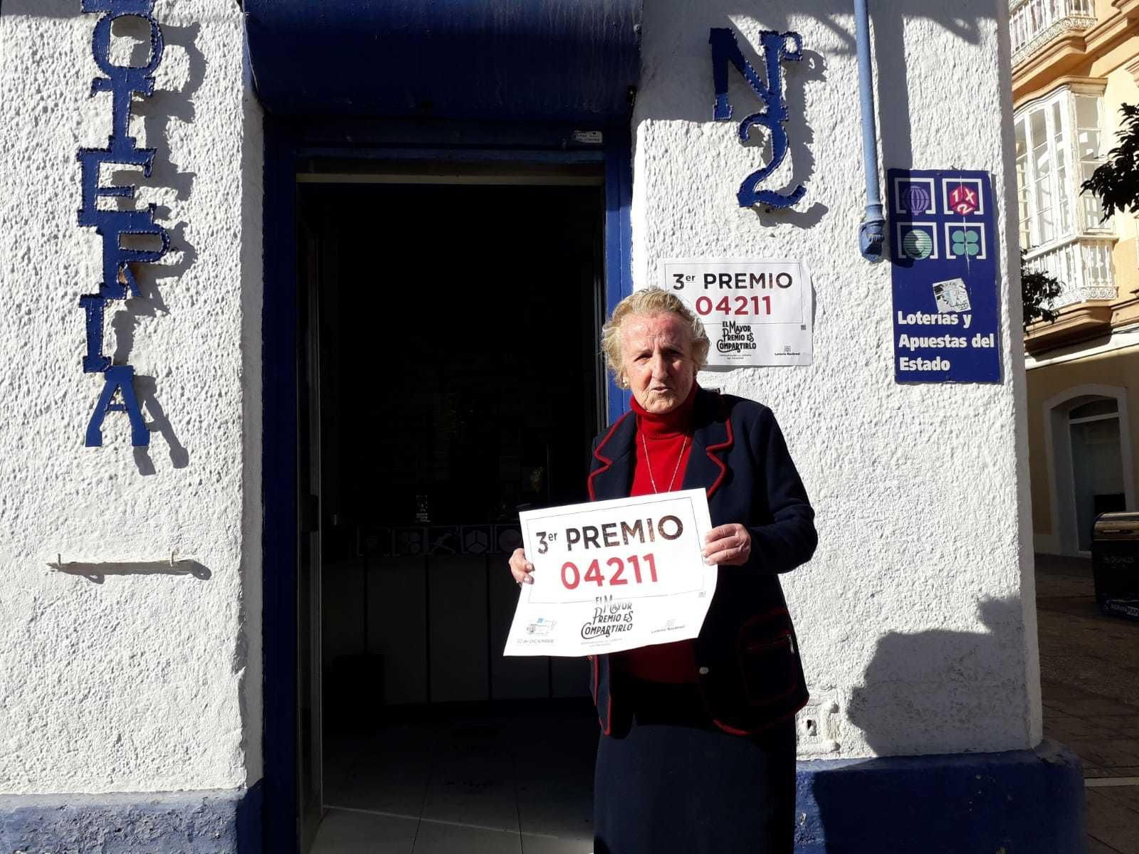 El número agraciado con el tercer premio se ha vendido también en la calle Real. En la imagen, Pilar Sevillano con el cartel del número premiado.