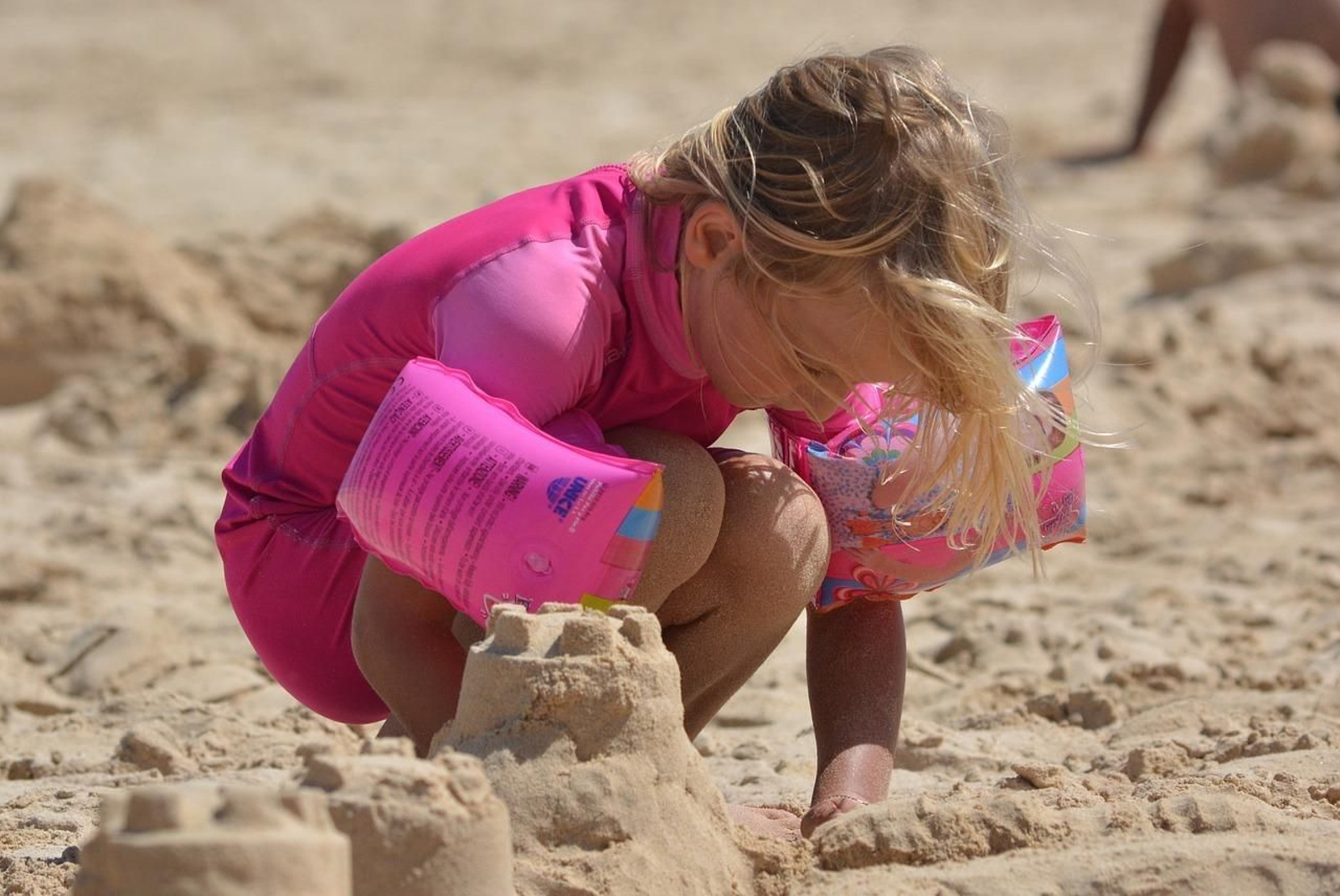 Niña haciendo un casillo de arena. Niña haciendo un casillo de arena.