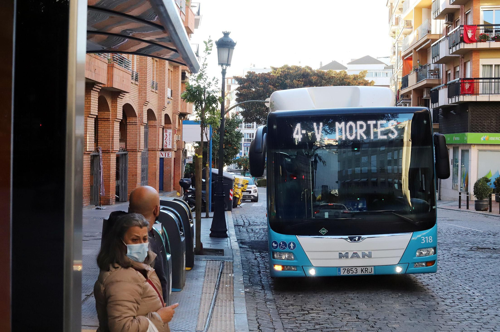 Dos personas esperan la llegada de un autobús urbano en una parada de la capital.
