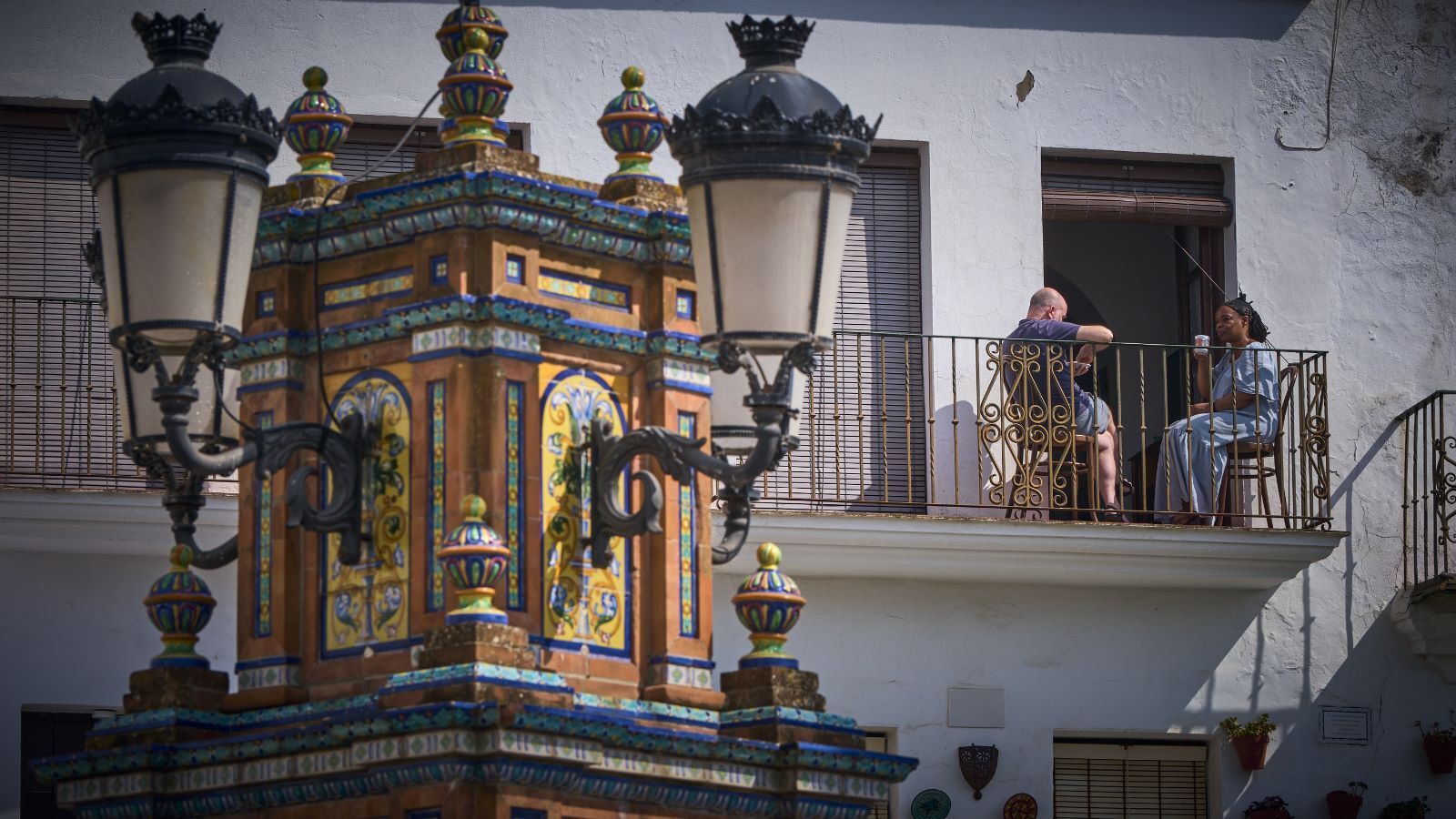 Dos personas toman un café en un balcón de la plaza de España de Vejer.