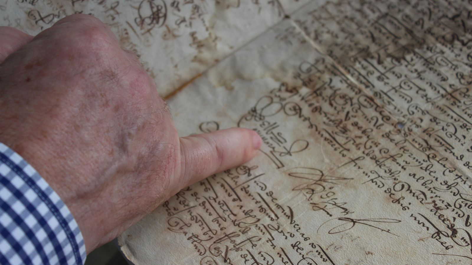 Gabriel Flores señala en uno de los legajos más antiguos que atesora el archivo.