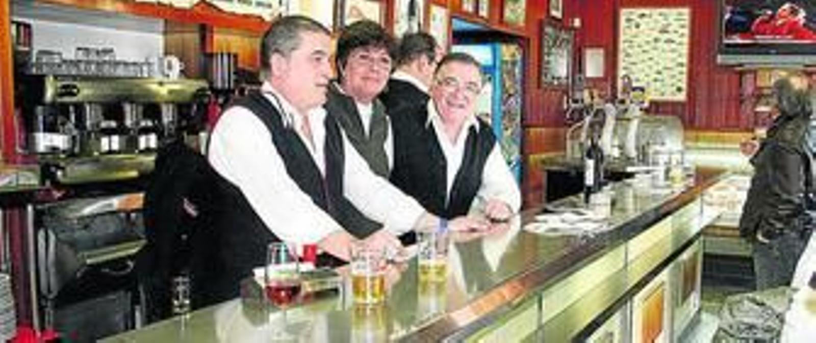Los camareros del bar restaurante El Rempujo, con una clienta que quiso despedirse detrás de la barra, en la última jornada de apertura del señero negocio.