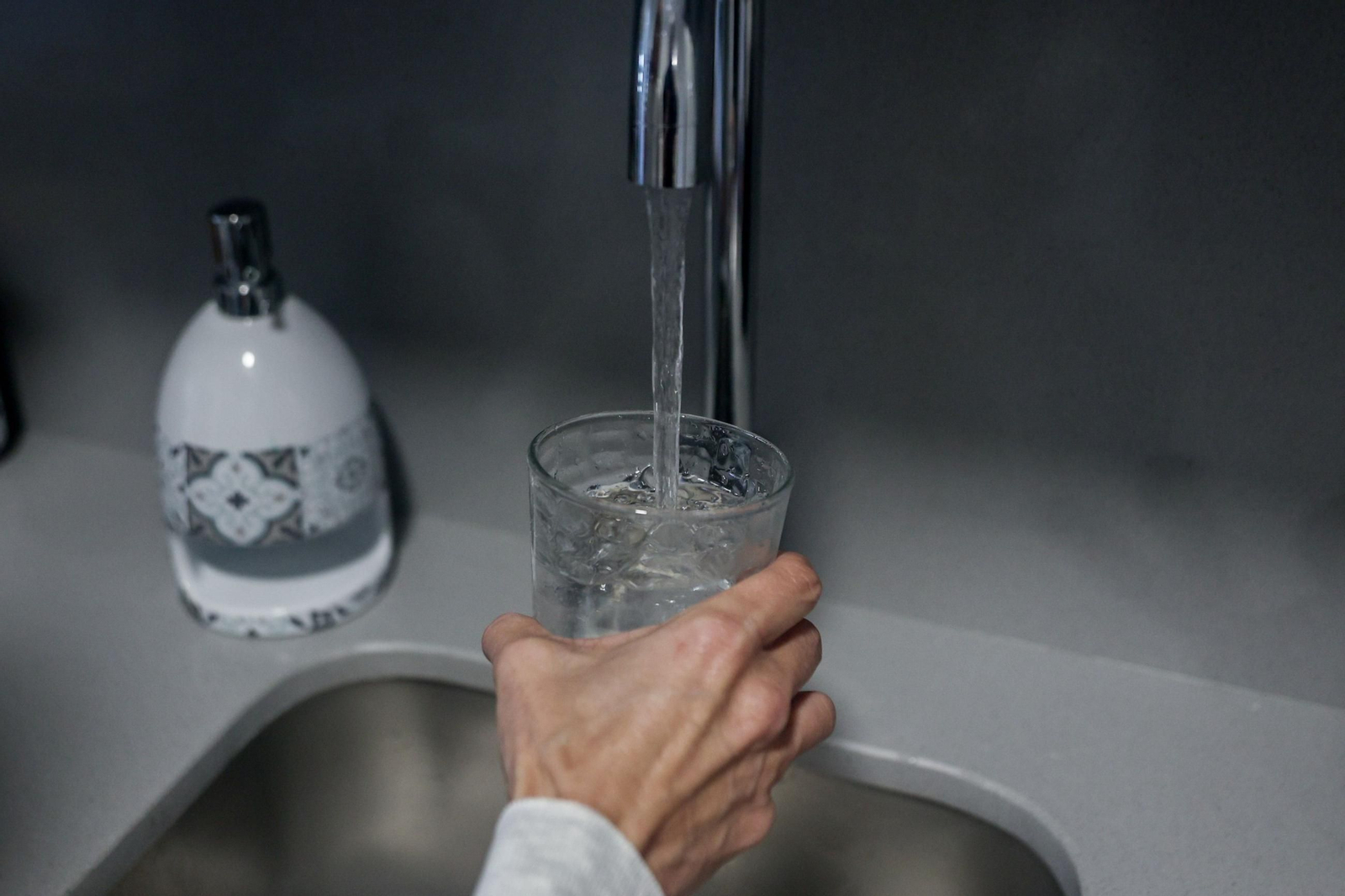 Una persona llena un vaso de agua.