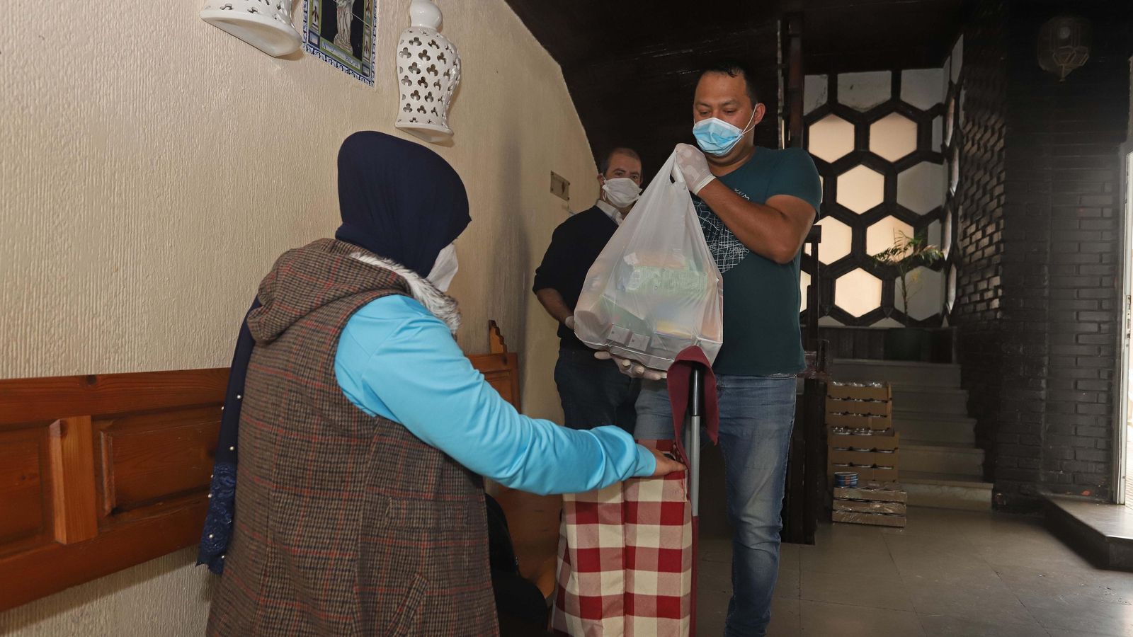 Dos personas recogen la bolsa con alimentos no perecederos en la parroquia de Nuestra Señora de la Palma, en Algeciras.