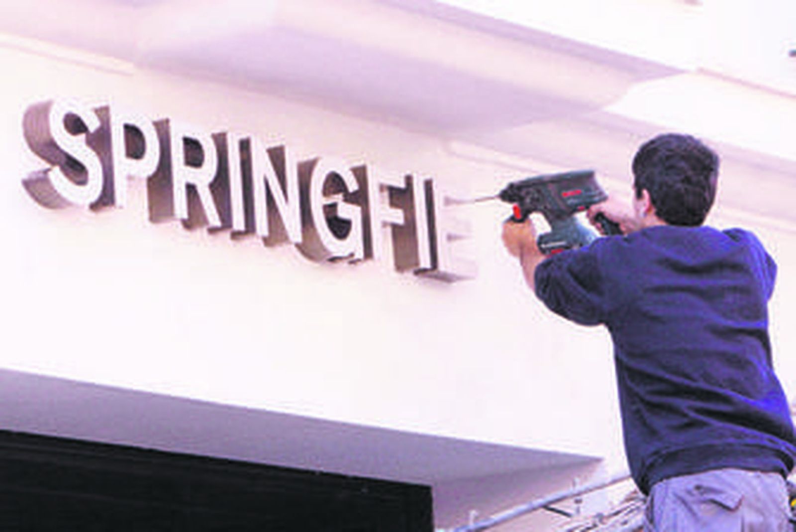 Un trabajador coloca el cartel del nuevo establecimiento que se sitúa frente al Ayuntamiento.