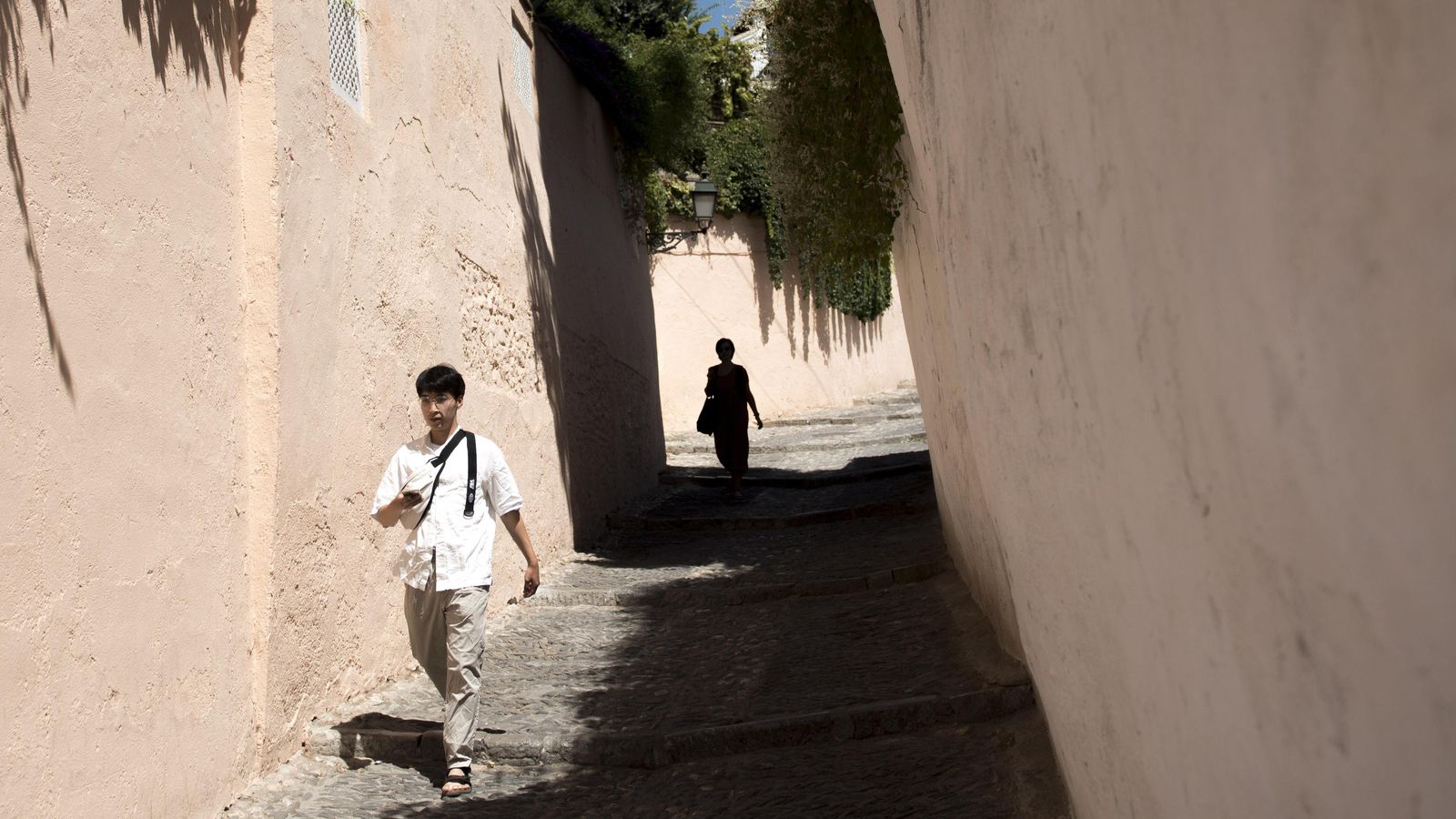 Un turista chino camina por el Albaicín guiándose con su movil Un turista chino camina por el Albaicín guiándose con su movil