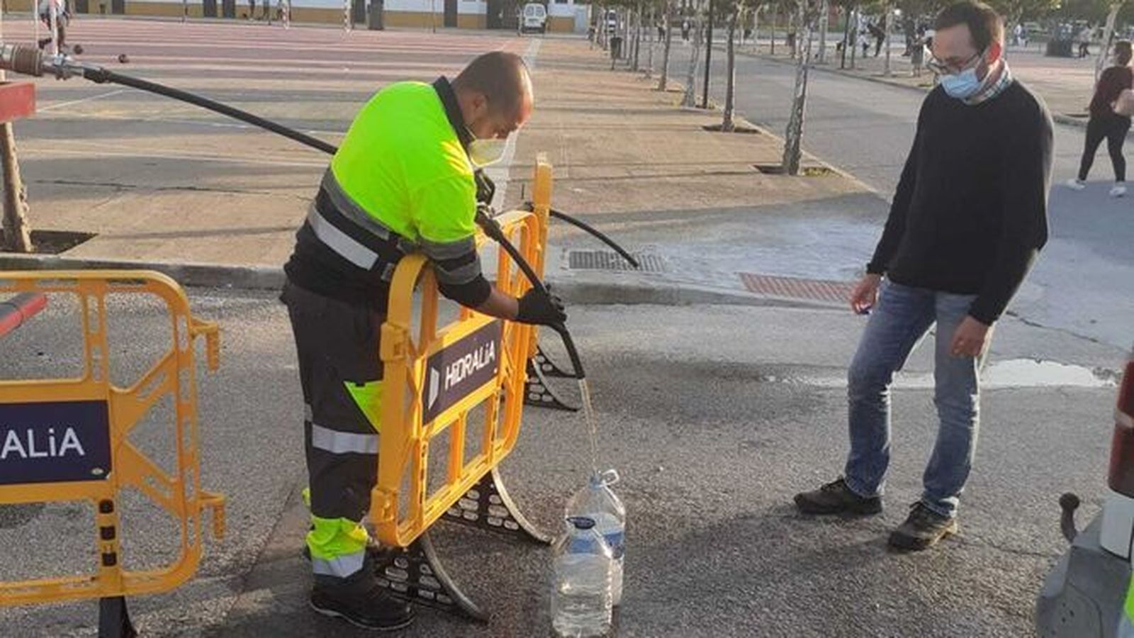 Un operario de Hidralia llena garrafas de agua procedente de una cuba, en Marchena.