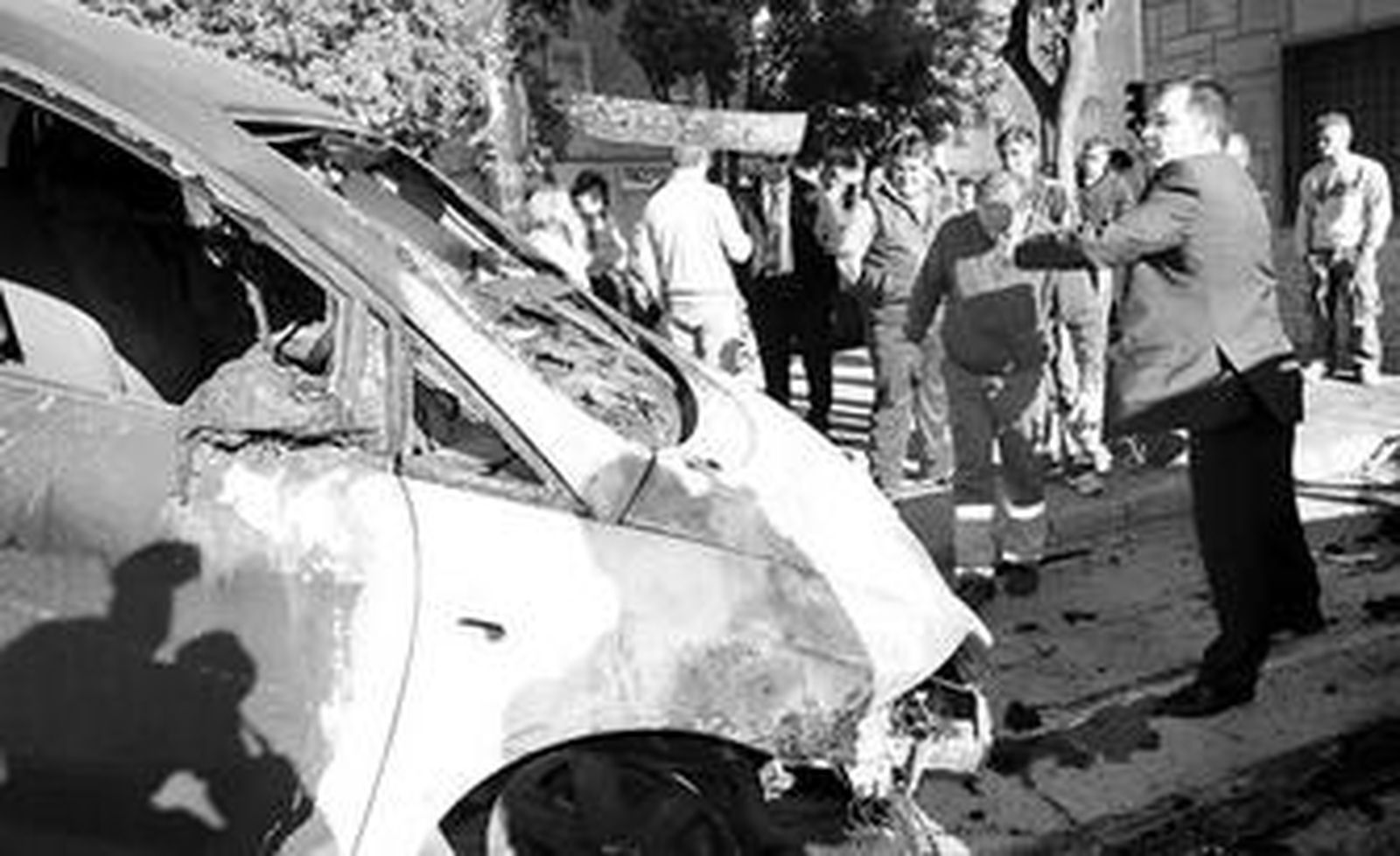 El propietario lanza ayer la placa de matrícula al interior del vehículo calcinado.