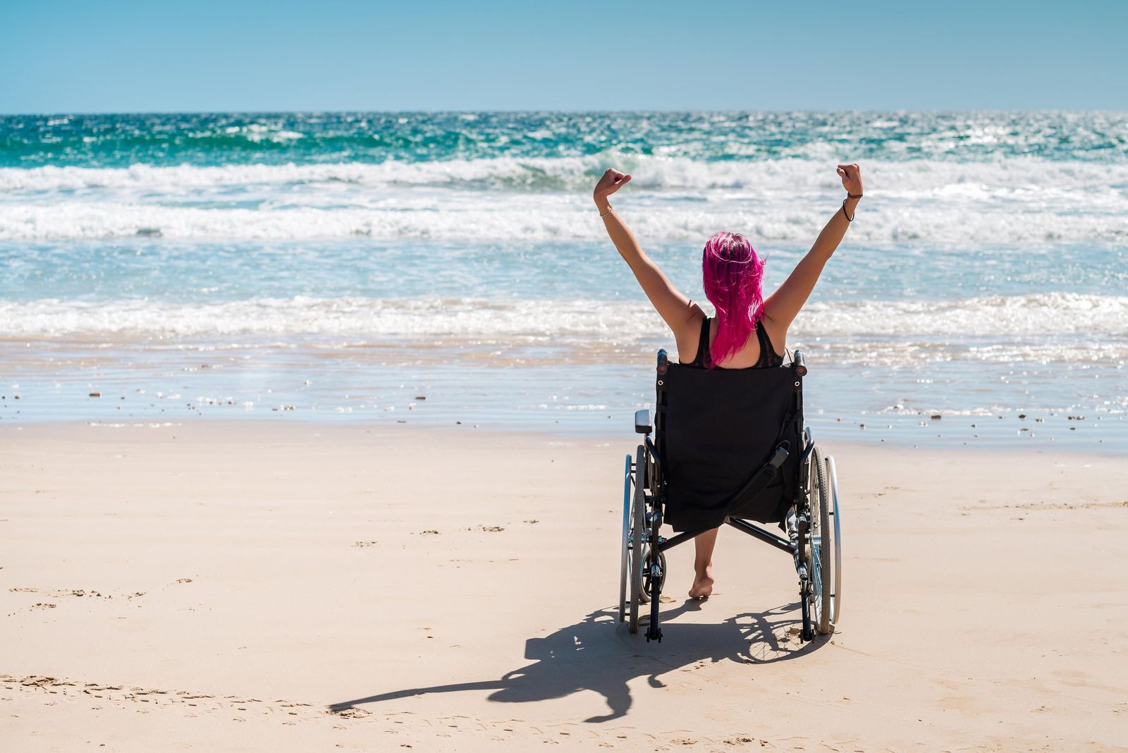 Una joven en silla de ruedas disfruta de la playa.